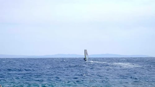 A man is engaged in windsurfing in the red sea, mountains in the background, water sport