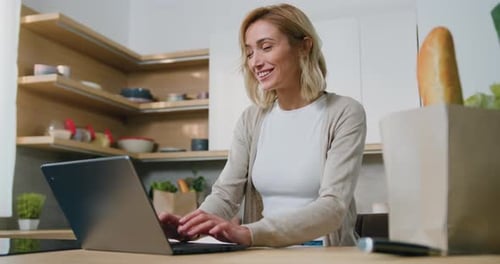 Woman Working on Laptop in Bright Kitchen
