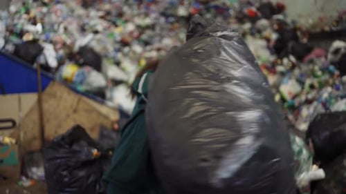 African American Woman Sorting Garbage Bags at a Recycling Plant