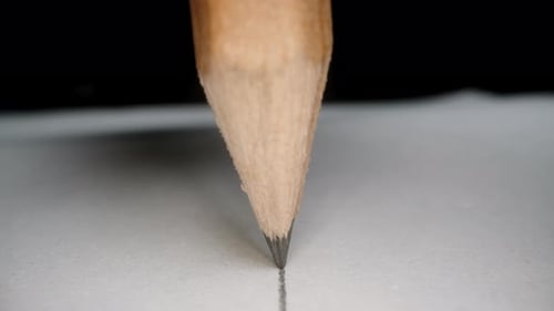 Pencil draws a straight line on paper, the camera follows it. Dolly slider extreme close-up.
