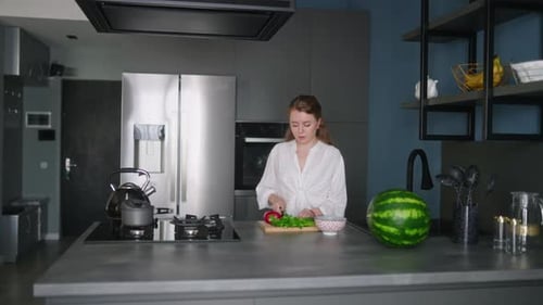 Caucasian Woman Making a Salad of Vegetables on Modern Kitchen Island Young Female Cuts the Greens