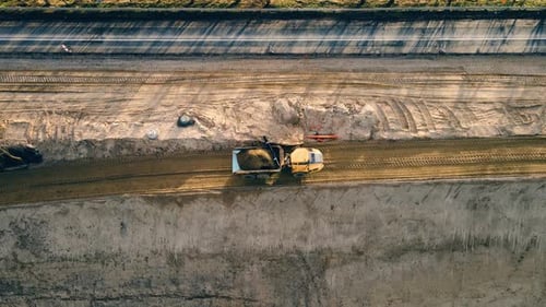 Large Quarry Dump Truck Full of Yellow Sand Driving By Gravel Path