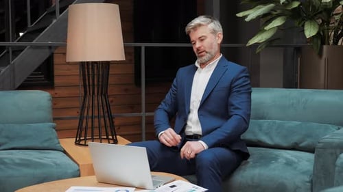 Businessman Works then Stretches on Teal Sofa