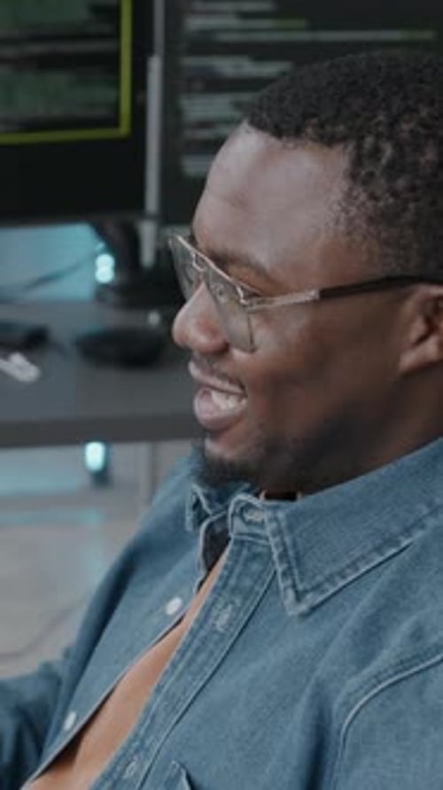 Vertical of Black Man Video Conferencing on Computer while Coding in Office