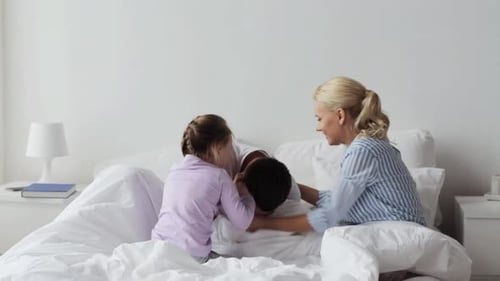 Happy Family Playing Together in Bed at Home