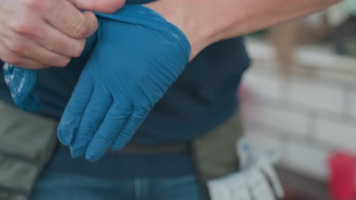 Gros plan d'un homme tirant et laissant tomber des gants jetables bleus