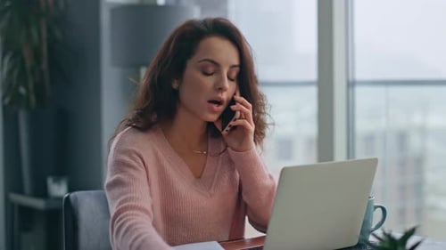Woman Talking on Phone While Working on Laptop