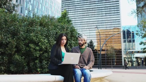 Business people sitting outside the office having a business meeting and using a laptop computer