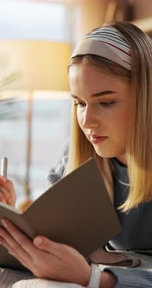 Woman Writing in Notebook With Pen at Home