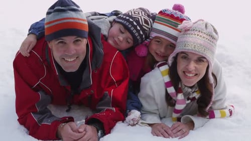 Family Laying In Winter Snow