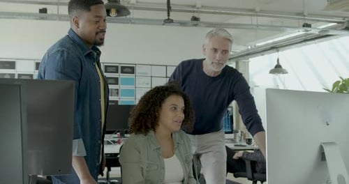 Group of Coworkers Meeting round a Desktop Computer in Discussion