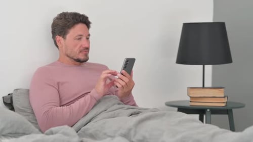 Man Using Smartphone Device in Bed