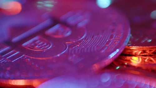 Extreme close-up of Bitcoin coin with vibrant purple and blue neon lighting, highlighting intricate