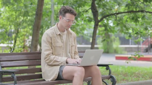 Modern Young Man Working on Laptop Sitting Outdoor