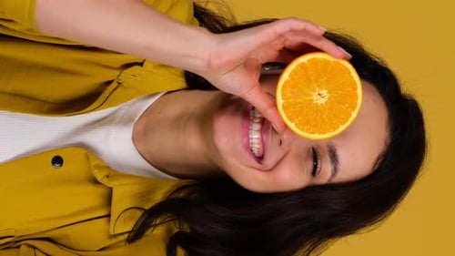 Woman Poses with Oranges on Yellow Background