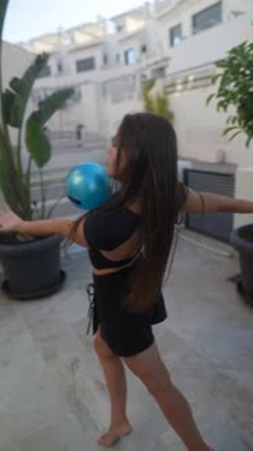 In a Garden a Carefree Girl Plays Joyfully with a Blue Ball Radiating Energy and Happiness