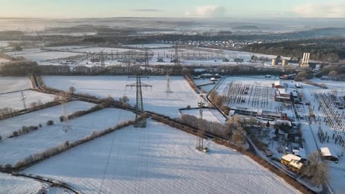 Aerial footage over industry utility power lines, pylon structure and substation in winter agricult