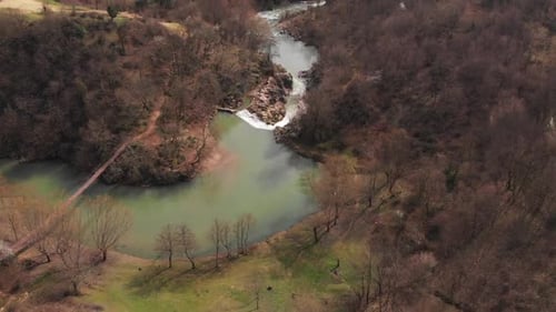 Aerial drone footage of beautiful lake and waterfall in a forest during spring