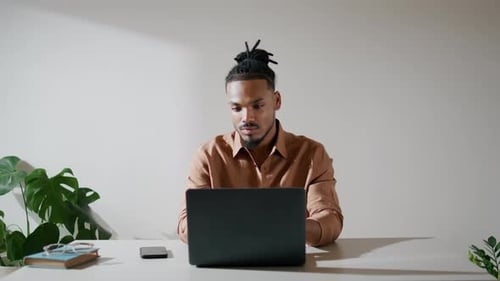 Man typing on a laptop computer indoors
