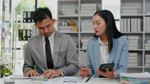 Professionals Reviewing Graphs at Desk in Office