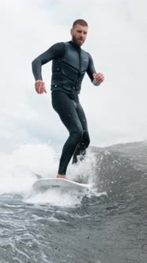 Man Rides Surfboard in Wetsuit on Ocean Wave