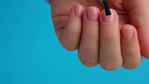 Clear Nail Polish Application on Blue Background
