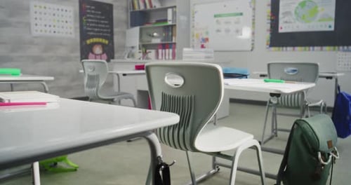 Interior of Empty Classroom with Desks and School Supplies Hanging Backpacks