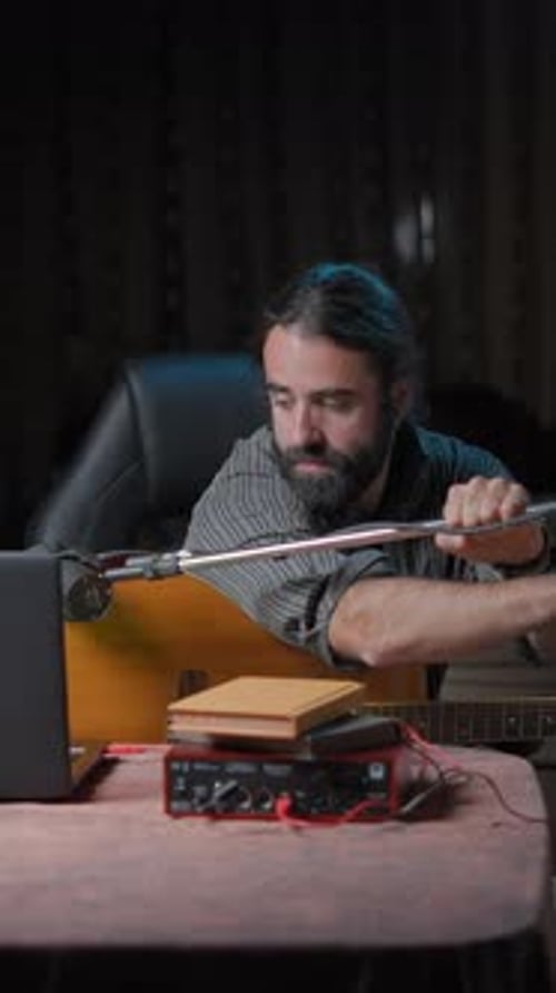 Jeune auteur-compositeur attrayant ajustant son trépied avant de se produire dans un concert en ligne