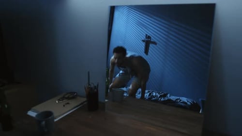 Worried Young Adult Approaches Mirror in Dark Room