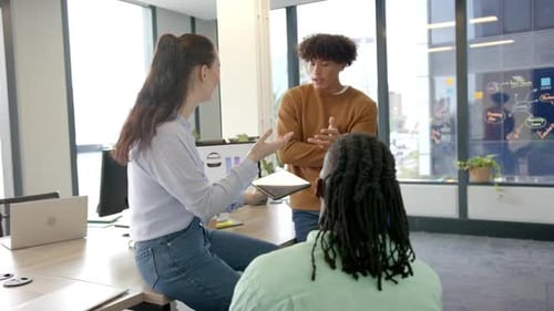 Collaborating with tablet and laptop, diverse colleagues discussing work in modern office