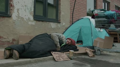 Tramp Sleeping on Cardboard with Sign on Street