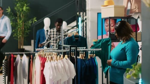 Clothing Boutique Customer Browsing, Shop Assistant Offering Help