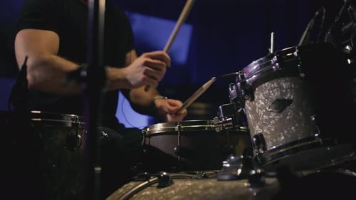 Drummer Playing Drum Set in Dimly Lit Setting