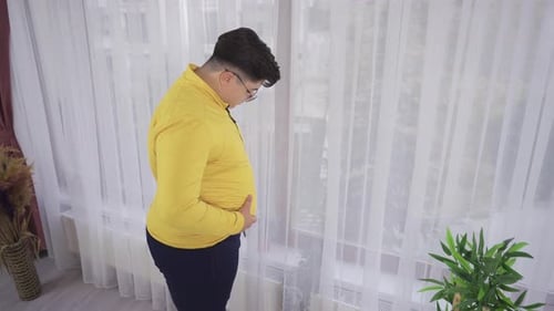 Young Adult Standing By Window Indoors