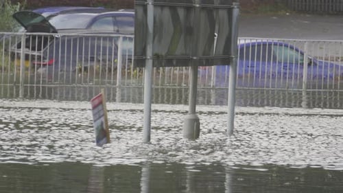 Water Rushing by on Flooded Roundabout with Cars Flooded and Submerged After Heavy Downpour