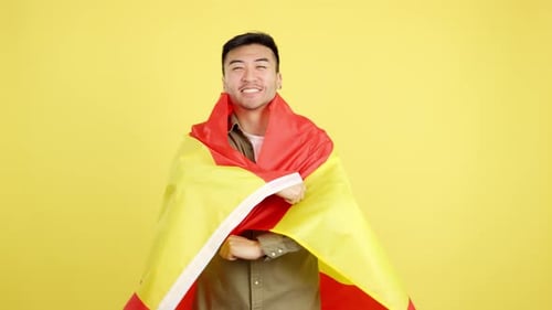 Smiling Young Adult Wraps in Spanish Flag