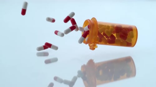 Pills Falling from Orange Medicine Bottle in Slow Motion