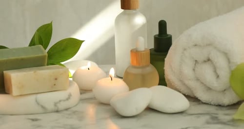Beautiful composition with spa products and burning candles on white table. Camera moving right