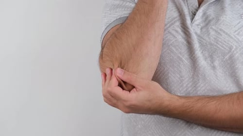 Man Rubbing His Elbow In Discomfort