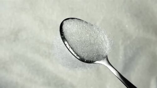 Zucker fließt aus einem Löffel, gefilmt mit einer Hochgeschwindigkeitskamera mit 1000 Bildern pro Sekunde