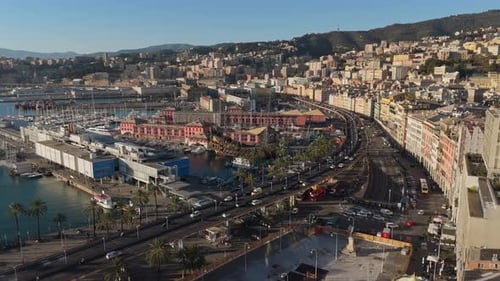 Sunset over Genoa's bustling port and historic buildings, with palm trees and traffic