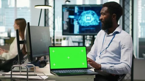 Programmeur de bureau en démarrage utilisant un ordinateur portable à écran vert pour développer des modèles d'IA
