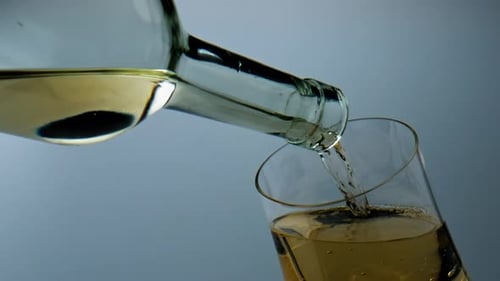 White Wine Pouring into Glass on Grey Background