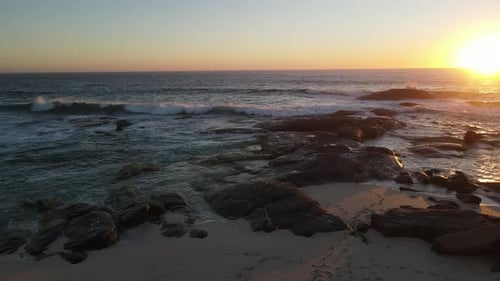 4K Amazing aerial shot attractive young male walking to play guitar on rocks front of wild sea waves