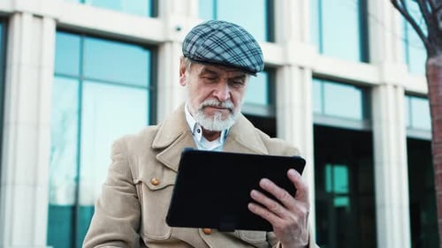 Closeup Portrait of Serious Elegant Handsome Mature Man Using Watching Typing on Tablet Wearing Coat