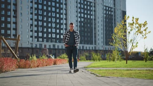 Young Man Walking on Sidewalk in Urban Setting