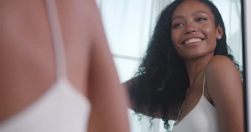 Smiling Woman Looks at Her Hair in Mirror