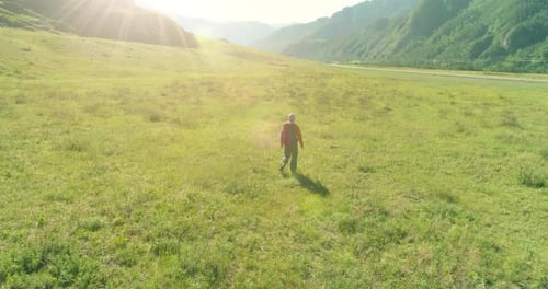 Flight Over Backpack Hiking Tourist Walking Across Green Mountain Field Huge Rural Valley at Summer