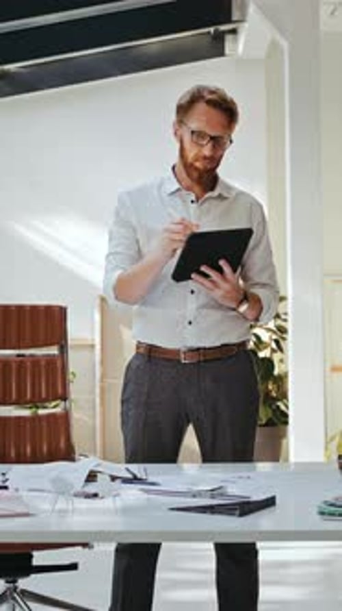 Mature Skillful Designer Using Tablet for Work at Office