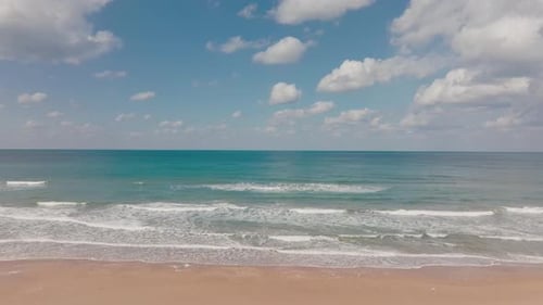Aerial view of clear Ocean water with blue cloudy sky